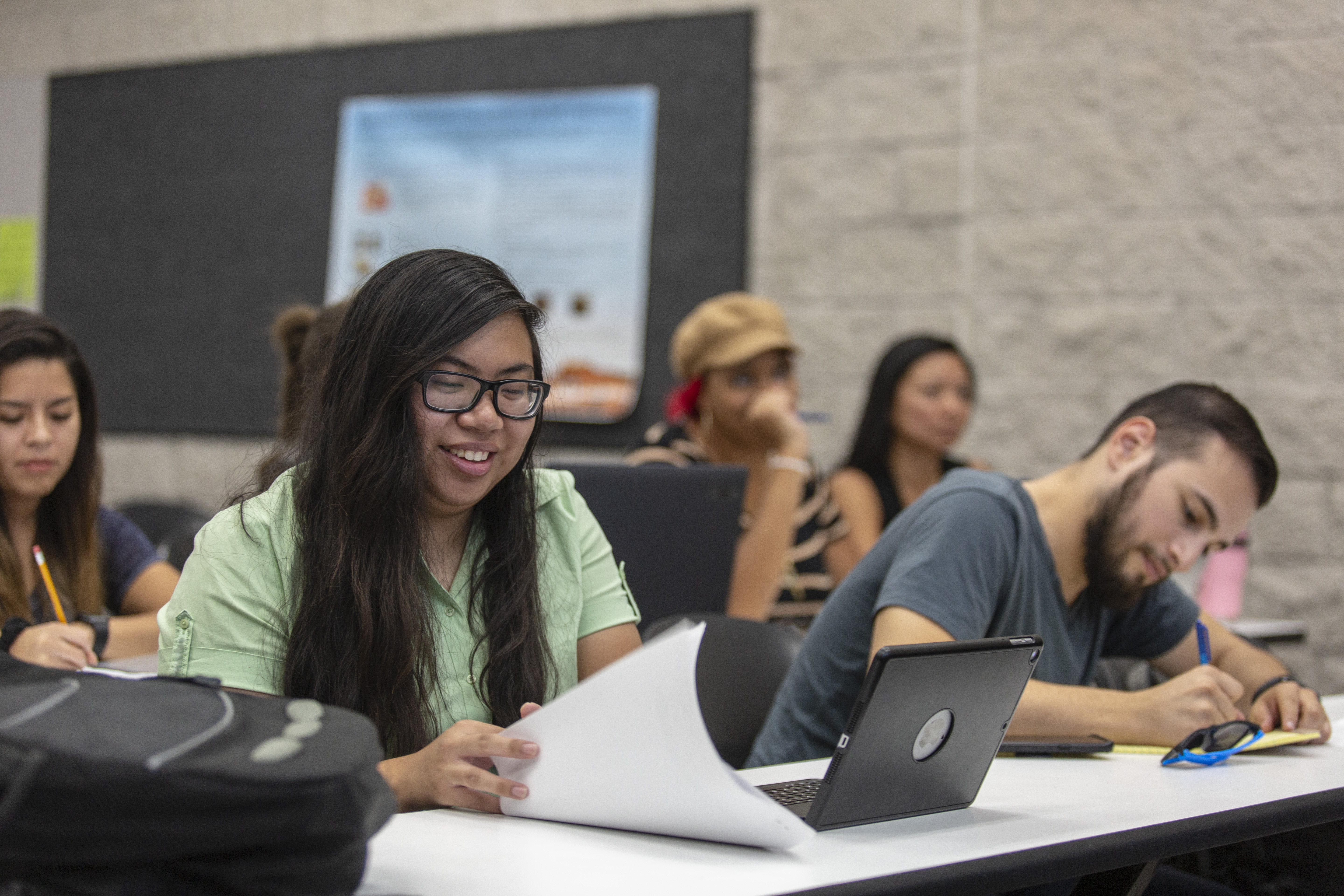 Student flipping through papers in a classroom.