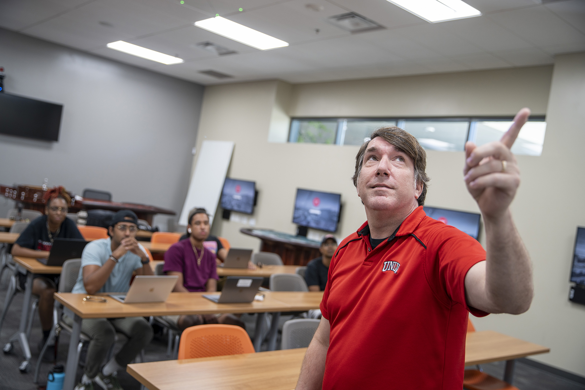 Person pointing to projector in a classroom. 