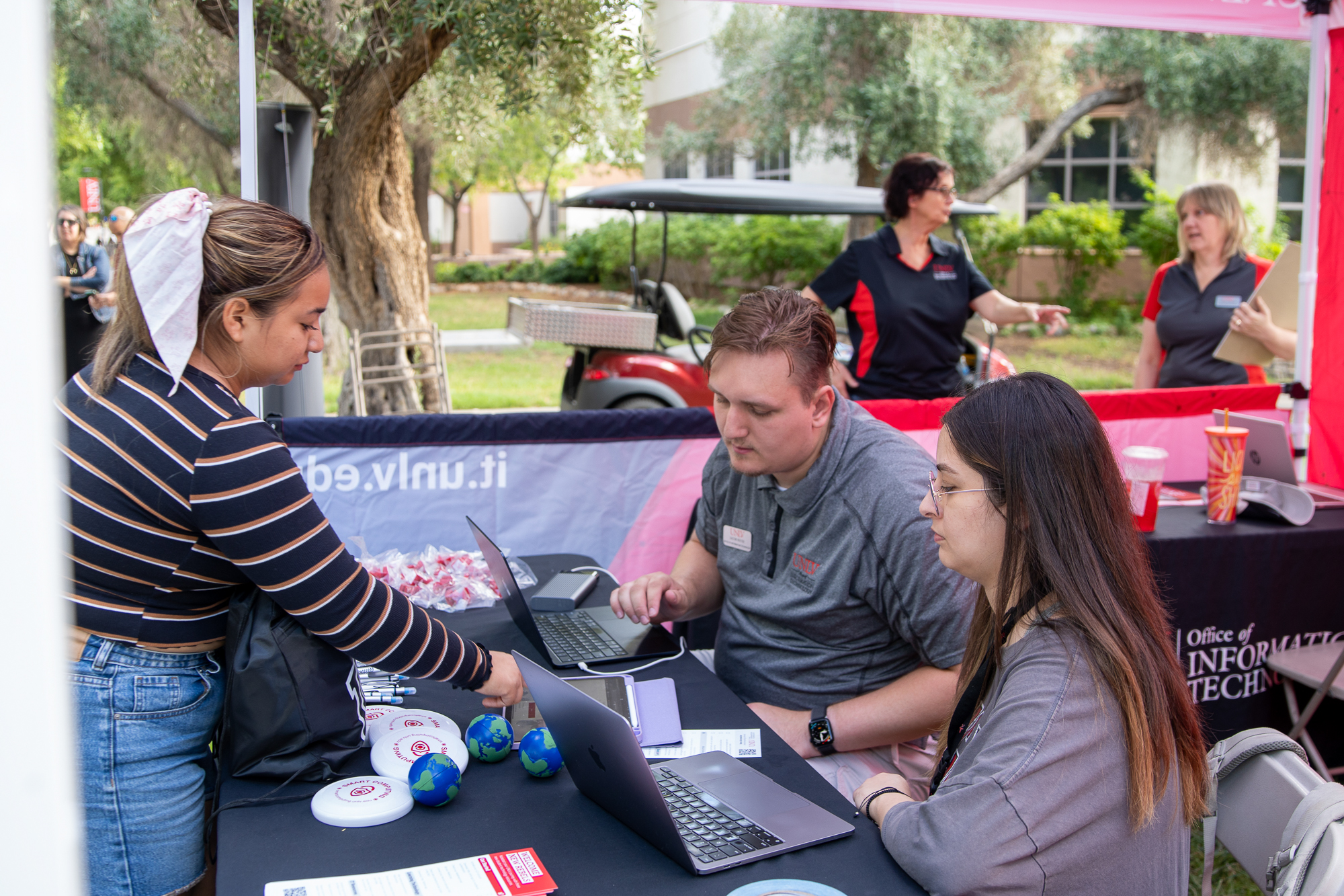 UNLV IT employees helping student with their tablet.