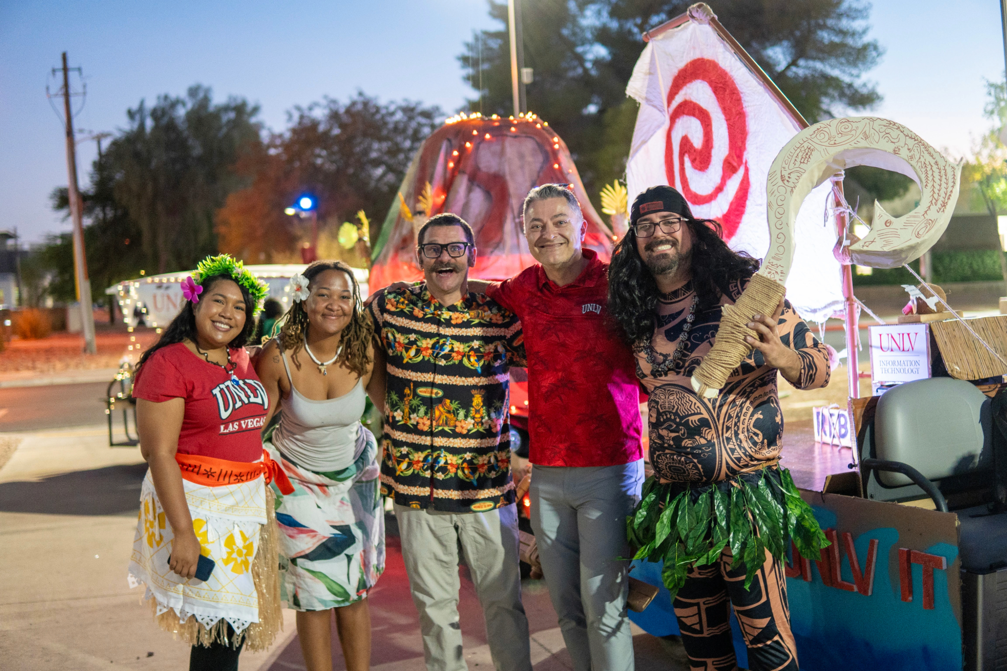 Group of people in costumes in front of decorated golf carts.