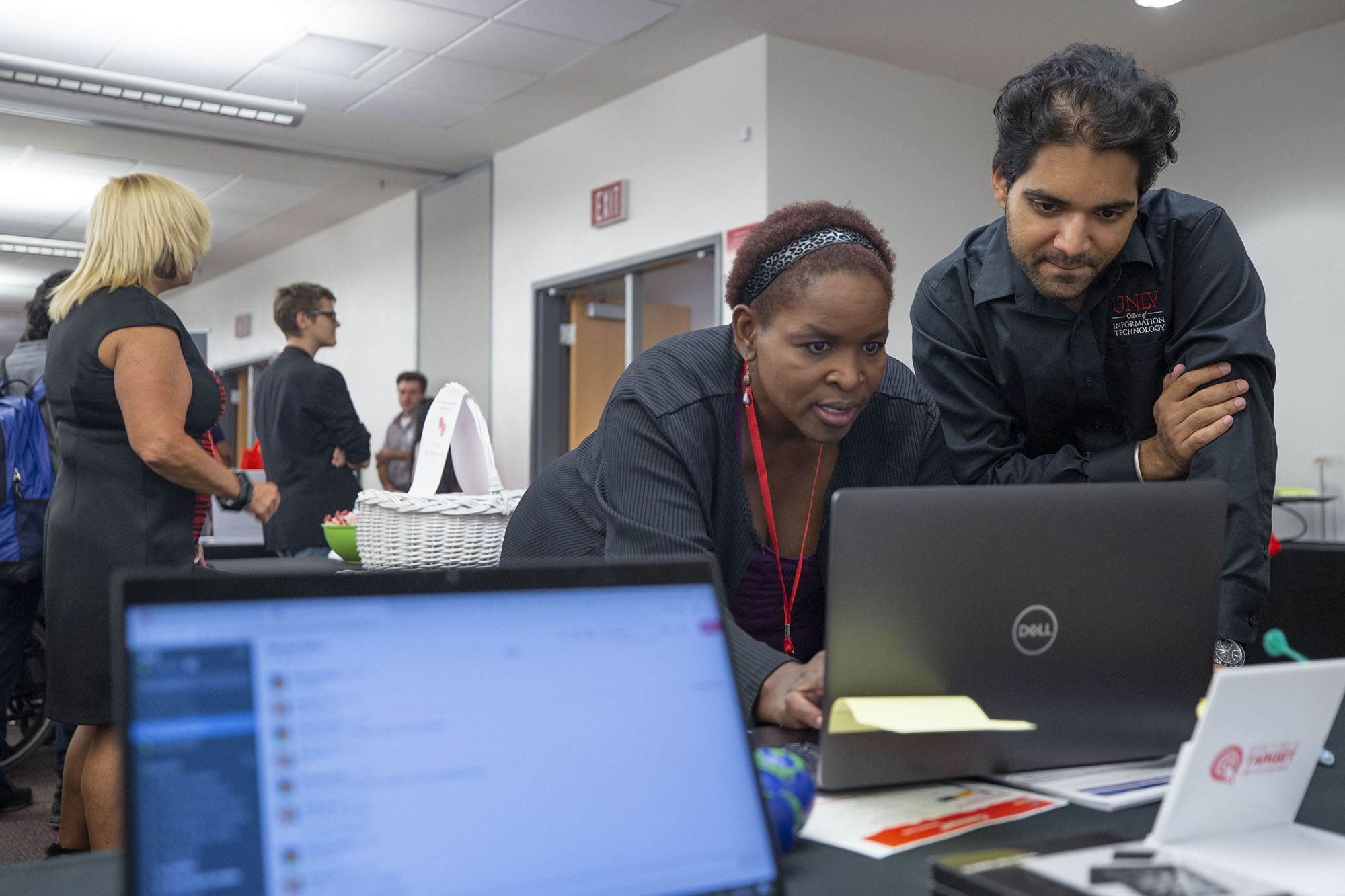 Two staff members peer down at a computer screen.