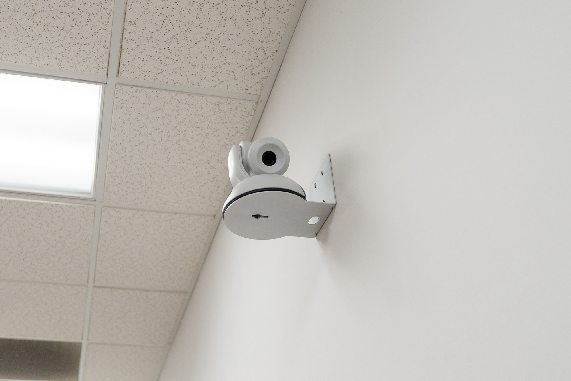 A lecture capture camera mounted on a white wall.