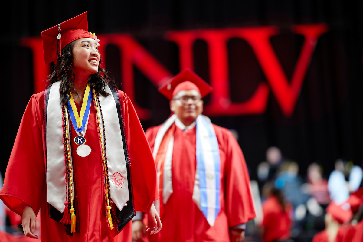 two unlv graduates walking towards the camera during commencement