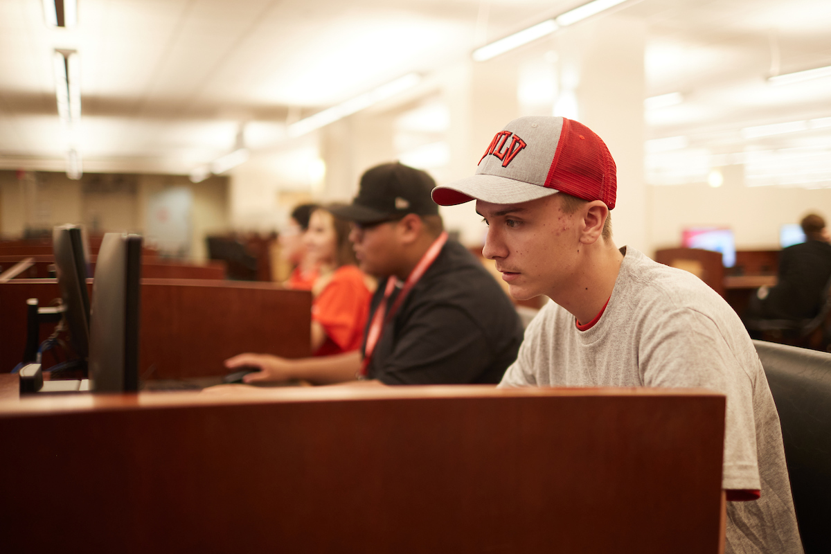 student wearing unlv cap using a library computer