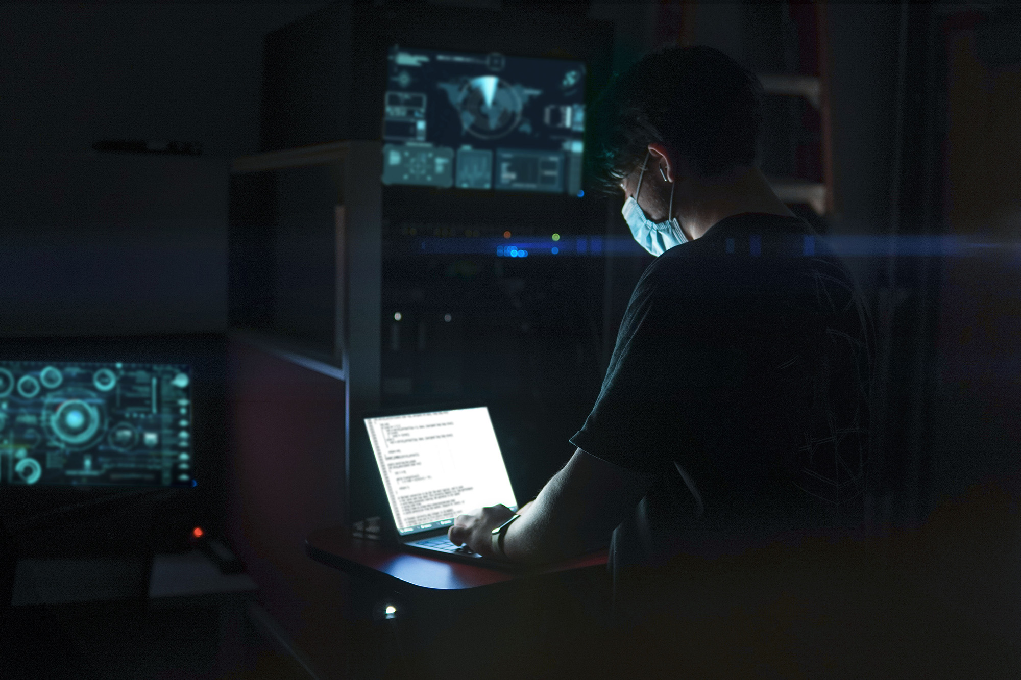 A person using a laptop computer in a dark room.