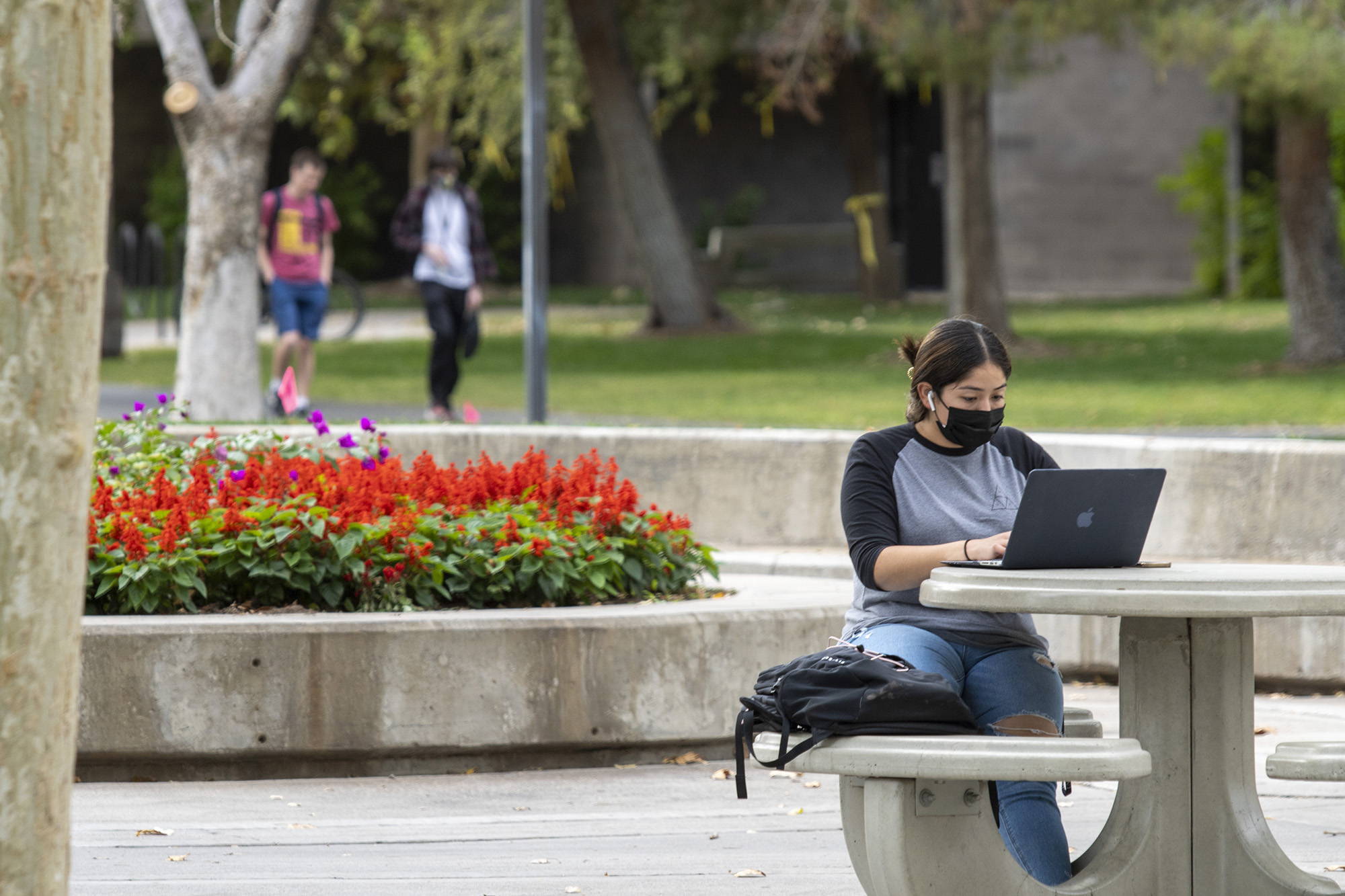Student wearing mask while using laptop computer outside