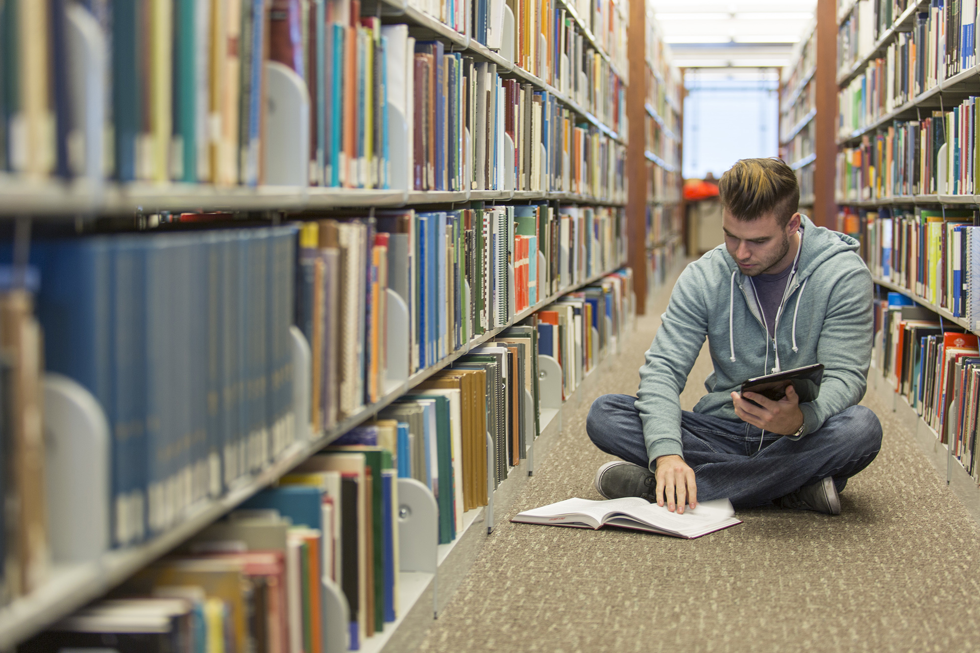 A male student studies between rows of books.