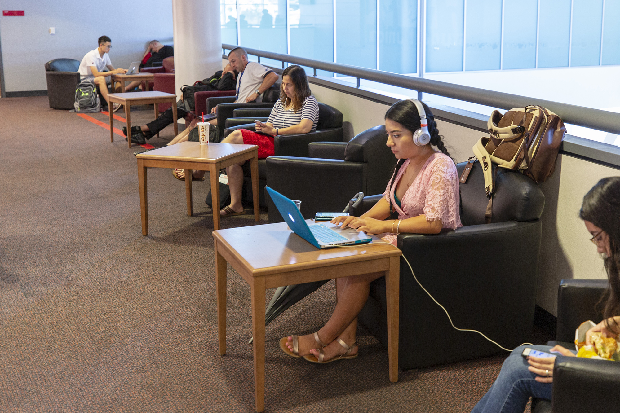 A female student wearing headphones peers down at her laptop.