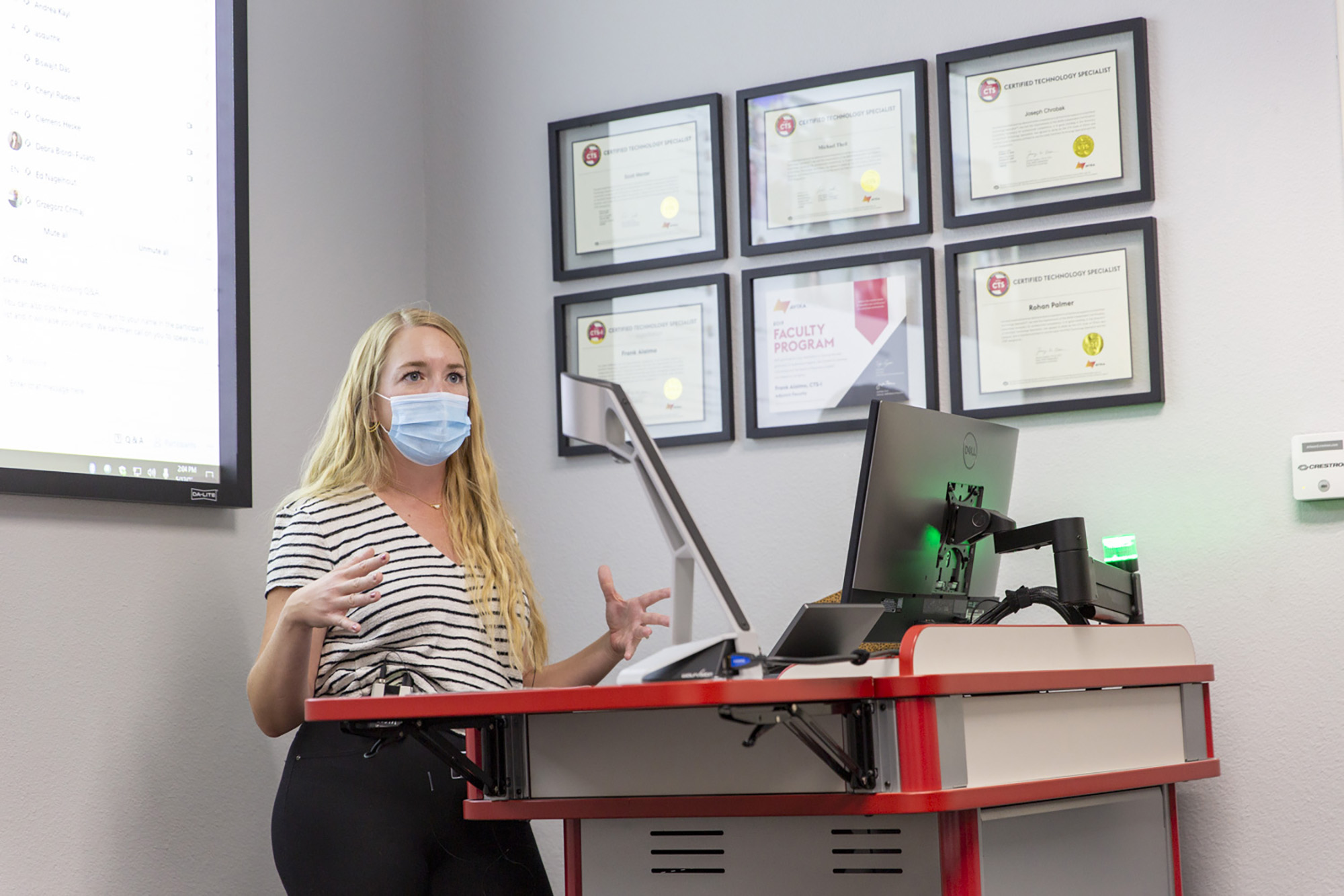 A masked instructor teaches a class from the lectern.