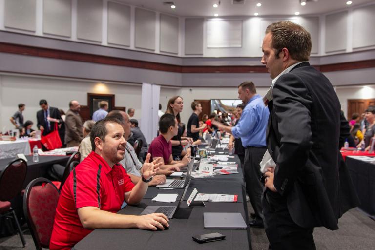 An IT staff member helps a faculty member at orientation.