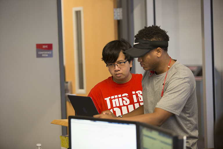 Two male students look at a tablet.