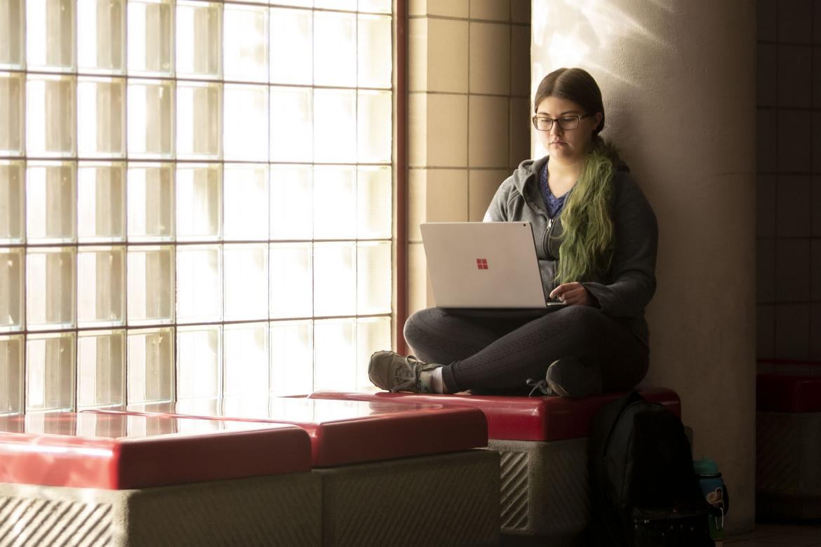 A female student gazes down at her laptop.