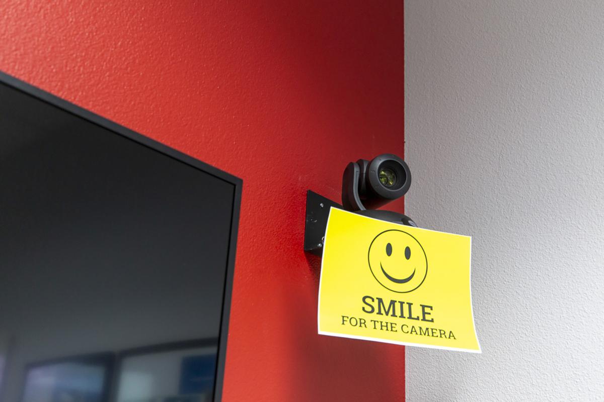 A UNLV conference room RebelFlex camera with a yellow "Smile for the camera" sign affixed. 