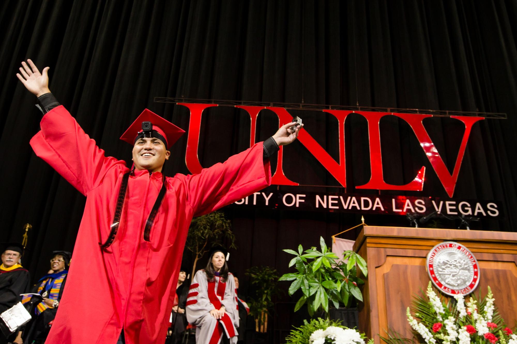 Person standing with arms open with UNLV in background