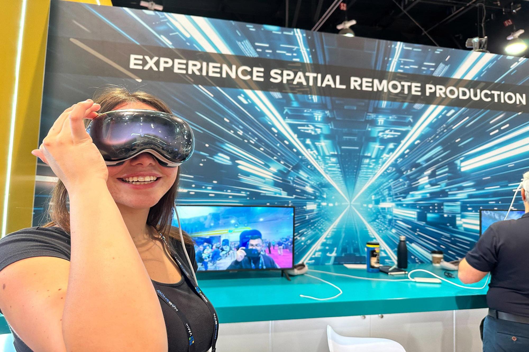 Person wearing headset smiling in front of a screen that says “Experience Spatial Remote Production”