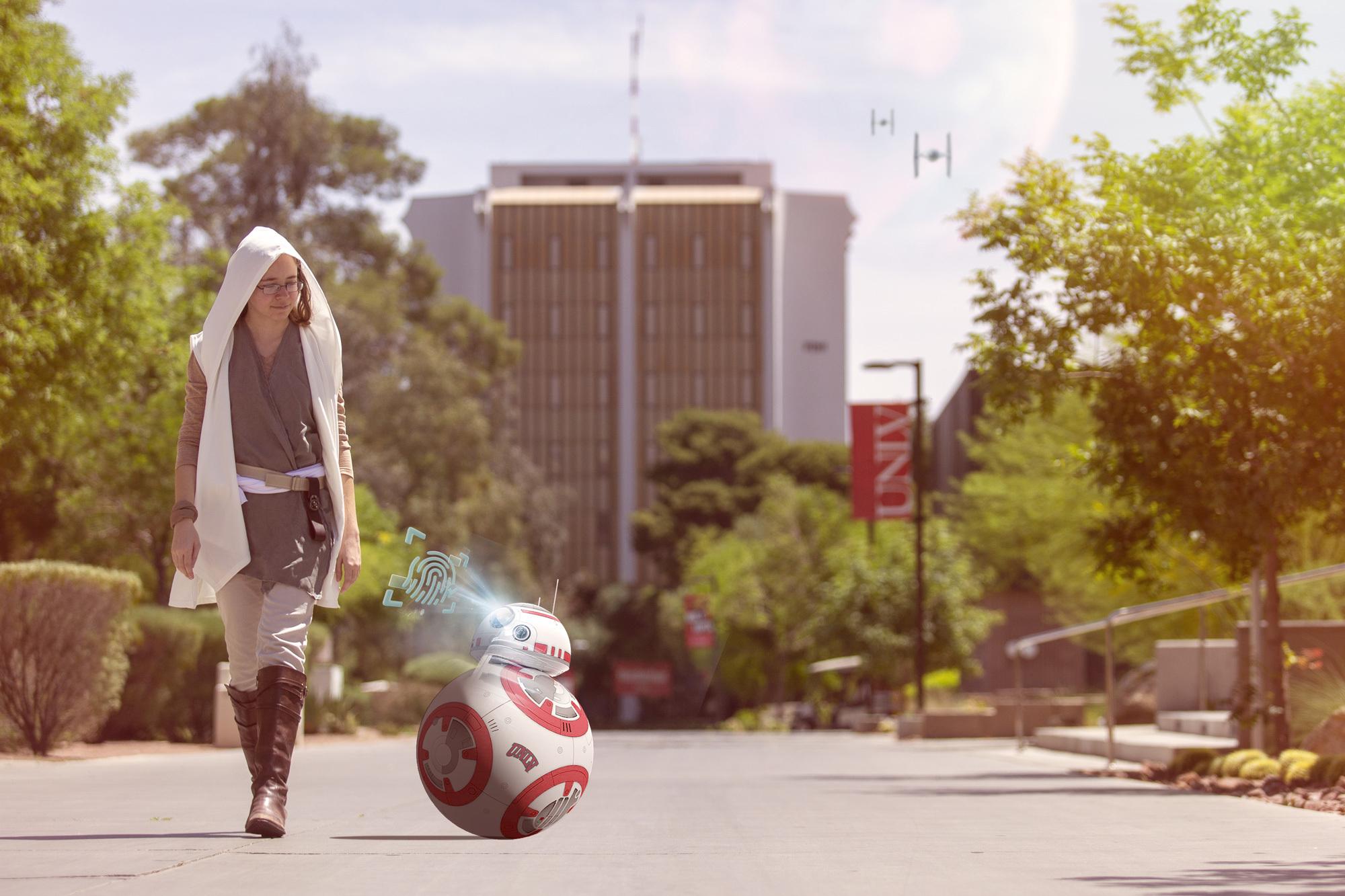 Person in a star wars costume walking with BB-8 robot on UNLV campus. 