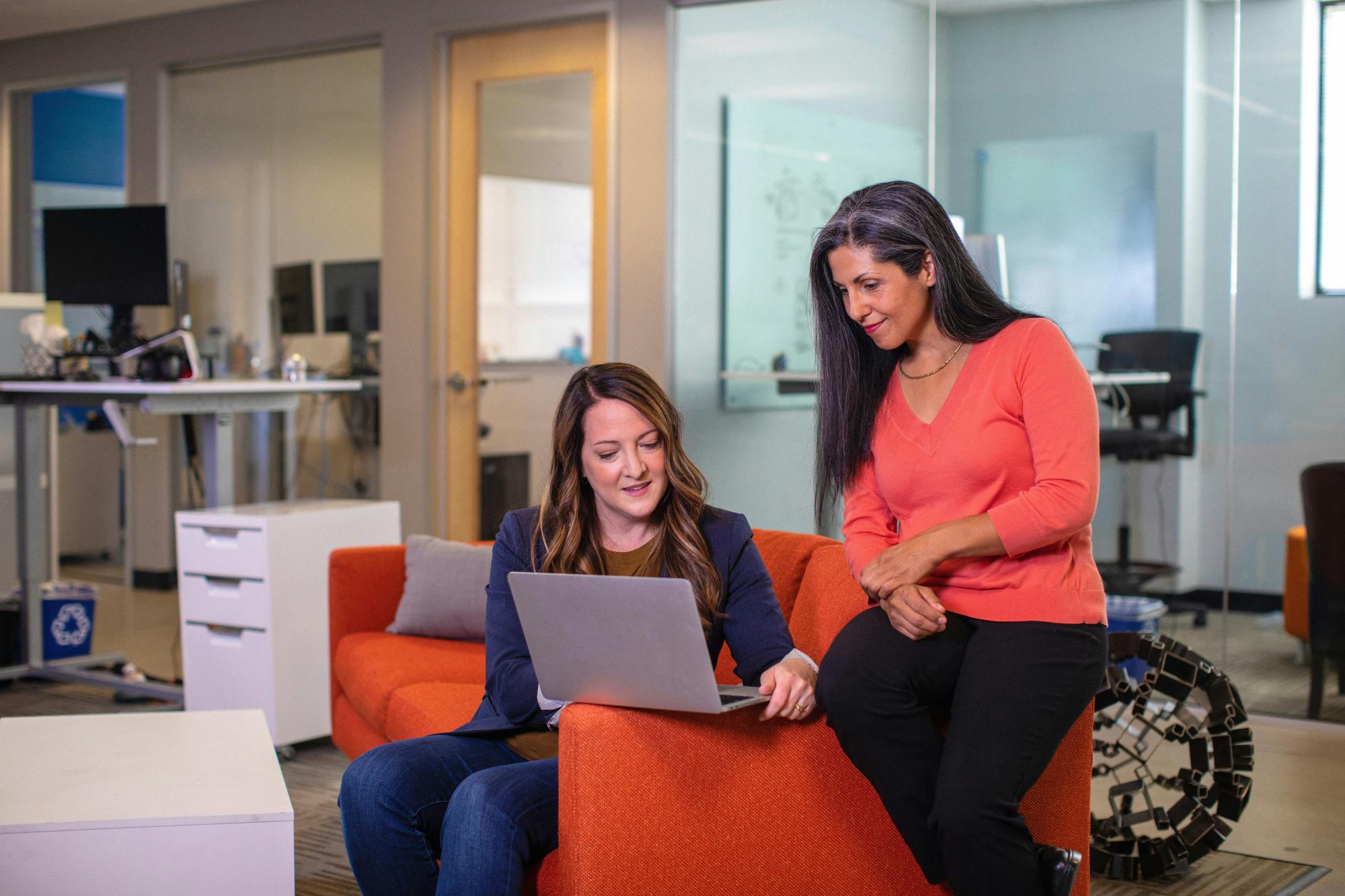 Two people sitting looking at a laptop computer in an office