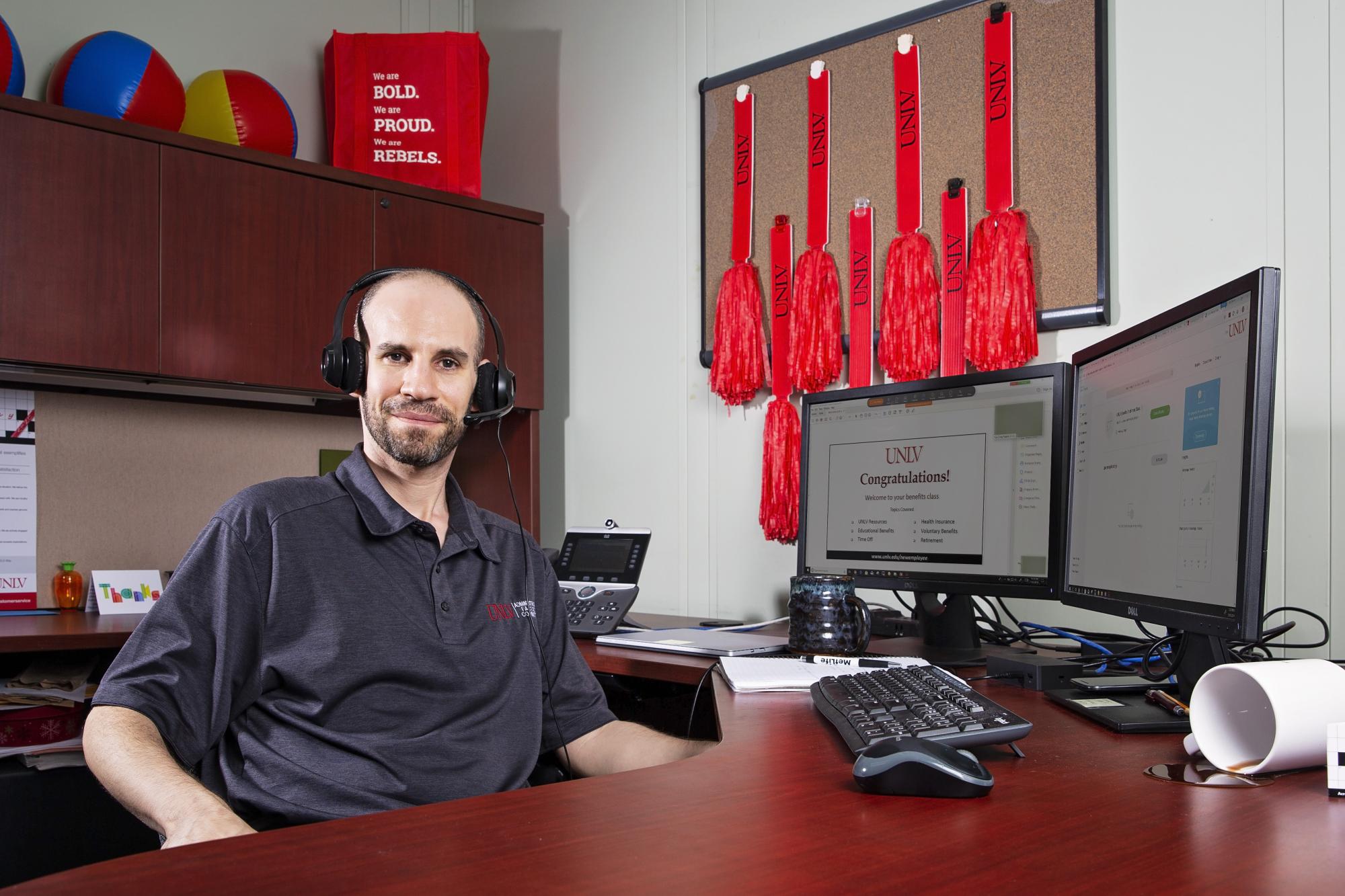 A person wearing headphones poses at their work station.