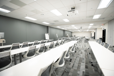 Large classroom with white desks and chairs that separates into three different classrooms. 