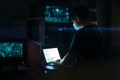 Person working on a laptop in a dark room.