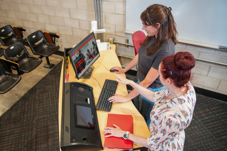 Two people standing at lecturn in classroom. 