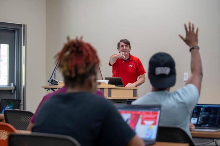 Person pointing at another person who is raising their hand