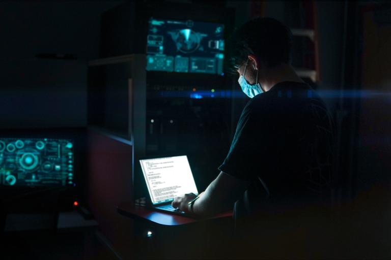 Person working on a laptop in a dark room.