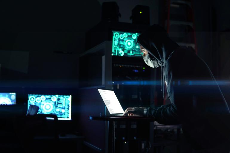 Person using laptop computer in dark room, cybersecurity awareness month