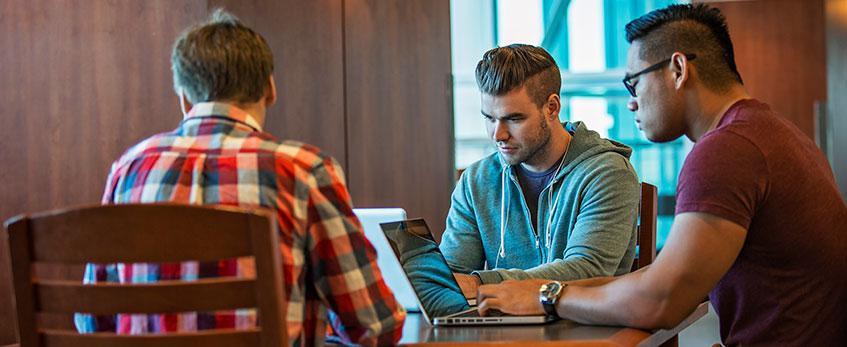 Three male students study on their laptops.